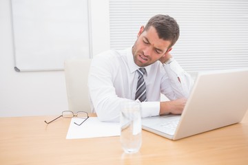 Confused businessman looking at his laptop