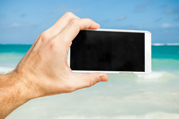 Man using smartphone for taking photo on a beach