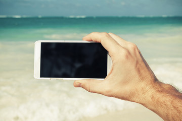 Man using smart phone for taking photo on a beach