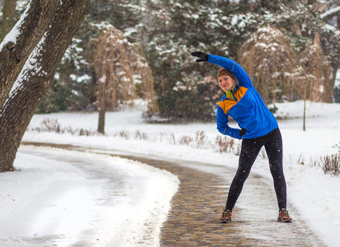 Athlete Woman Doing Exercises In Cold Snow Weather In Park