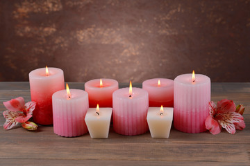Beautiful candles with flowers on table on brown background