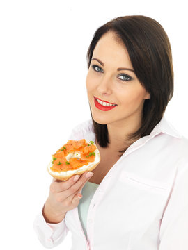 Young Woman Eating Smoked Salmon And Cream Cheese Bagel