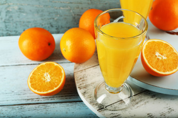 Glass of orange juice with slices on color wooden background