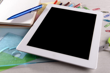 Tablet PC with office supplies on desktop background