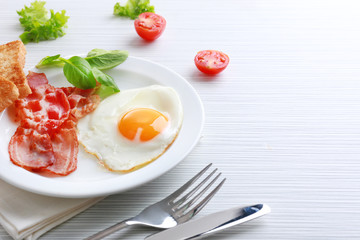 Bacon and eggs on color wooden table background