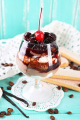 Tasty tiramisu dessert in glass, on color wooden background