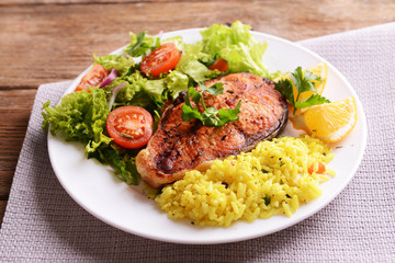 Tasty baked fish with rice on plate on table close-up
