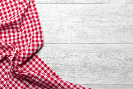 Red checkered tablecloth on white wooden table background