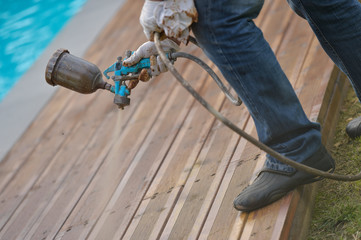 Spraying wood deck with spray gun