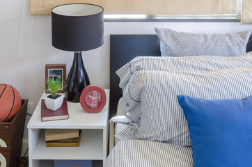 blue pillow on modern bed with black lamp on white table