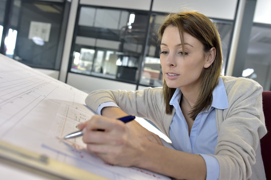 Woman engineer working on blueprint in office