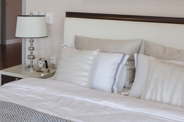 luxury bedroom with white classic lamp and clock on table