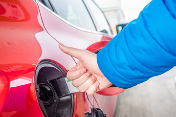 price of gas is very low, adult man with thumbs up close to his car after loading it with low price gasoline