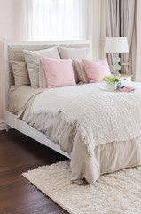 pink pillows on bed with white tray of flower at home