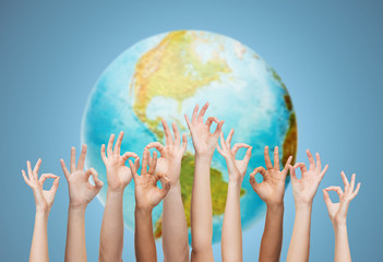 human hands showing ok sign over earth globe