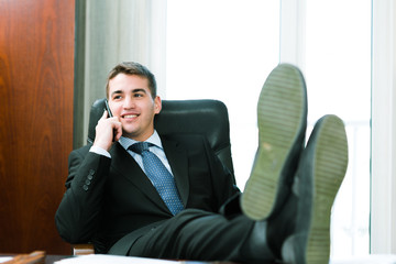 Businessman sitting in a chair and talking on mobile phone