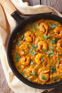 Shrimp in curry sauce in a pan close-up Vertical top view