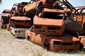 Stack of damaged rusted car scraps on junkyard
