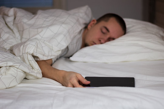 Man sleeping in bed and holding a tablet computer