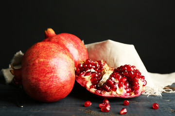 Juicy ripe pomegranates on wooden table, on dark background