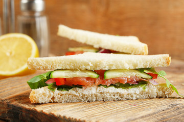 Club sandwich with salmon on wooden background