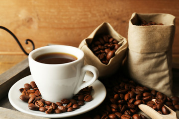 Cup of coffee with beans on tray and rustic wooden background