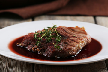 Grilled steak in wine sauce on plate on table close up