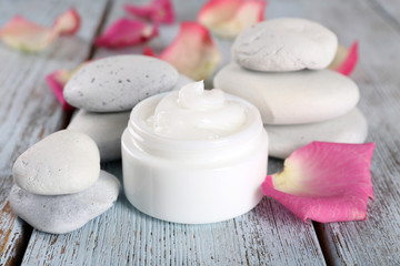 Fototapeta na wymiar Cosmetic cream with rose petals and spa stones
