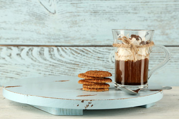 Cup of coffee with cream and cookies on wooden background