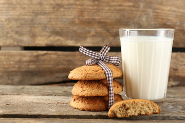 Tasty cookies and glass of milk on rustic wooden background