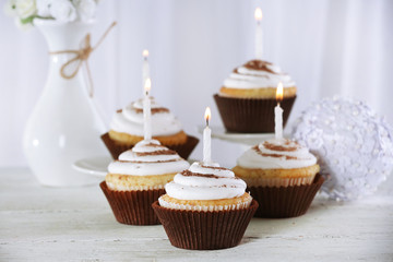Delicious birthday cupcakes on table on light background