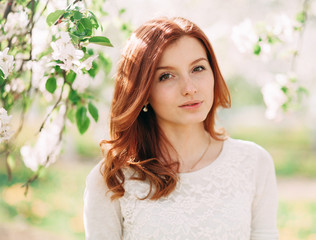 Young beautiful redhead woman in blooming garden