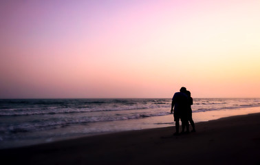 silhouette of couples hugging on the beach