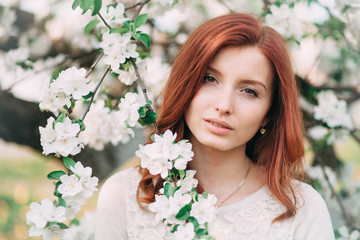 Naklejka premium Young sensual redhead woman in a blossoming trees