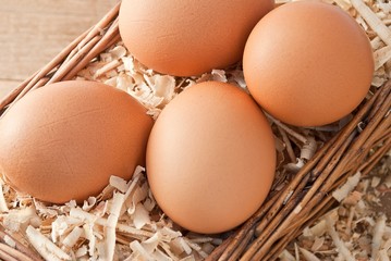 Egg on sawdust with old basket over on wooden background