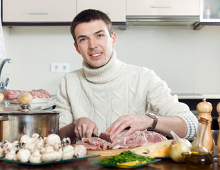  man cooking french-style meat. Adding grating cheese in roastin