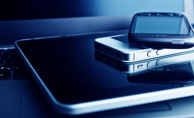 two phones and tablet pc on laptop
