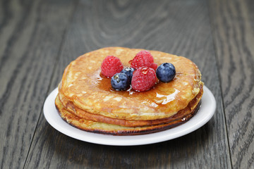 Pancakes with berries and maple syrup, on wooden table
