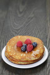 Pancakes with berries and maple syrup, on wooden table