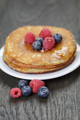 Pancakes with berries and maple syrup, on wooden table