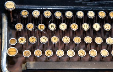 ancient black rusty typewriter with white keys - obrazy, fototapety, plakaty