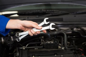 Mechanic holding pair of wrenches