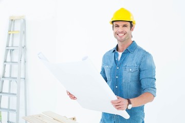 Happy architect holding blueprint in house