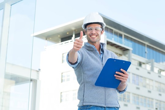 Happy architect with clipboard gesturing thumbs up