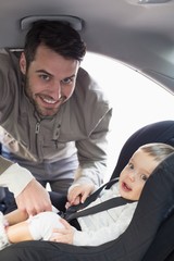 Father securing baby in the car seat