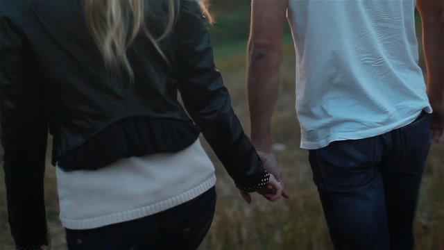 Young couple in love holding hands walking. Slow motion