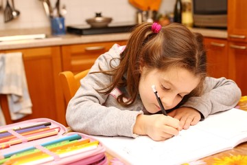 young girl writes with pencil on the school book