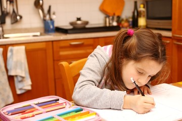 pretty girl writes with pencil her homework in the kitchen