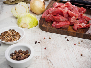 raw meat slices on cutting board with pepper and onion