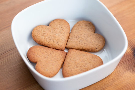 Four heart-shaped homemade cookies inside a white bowl